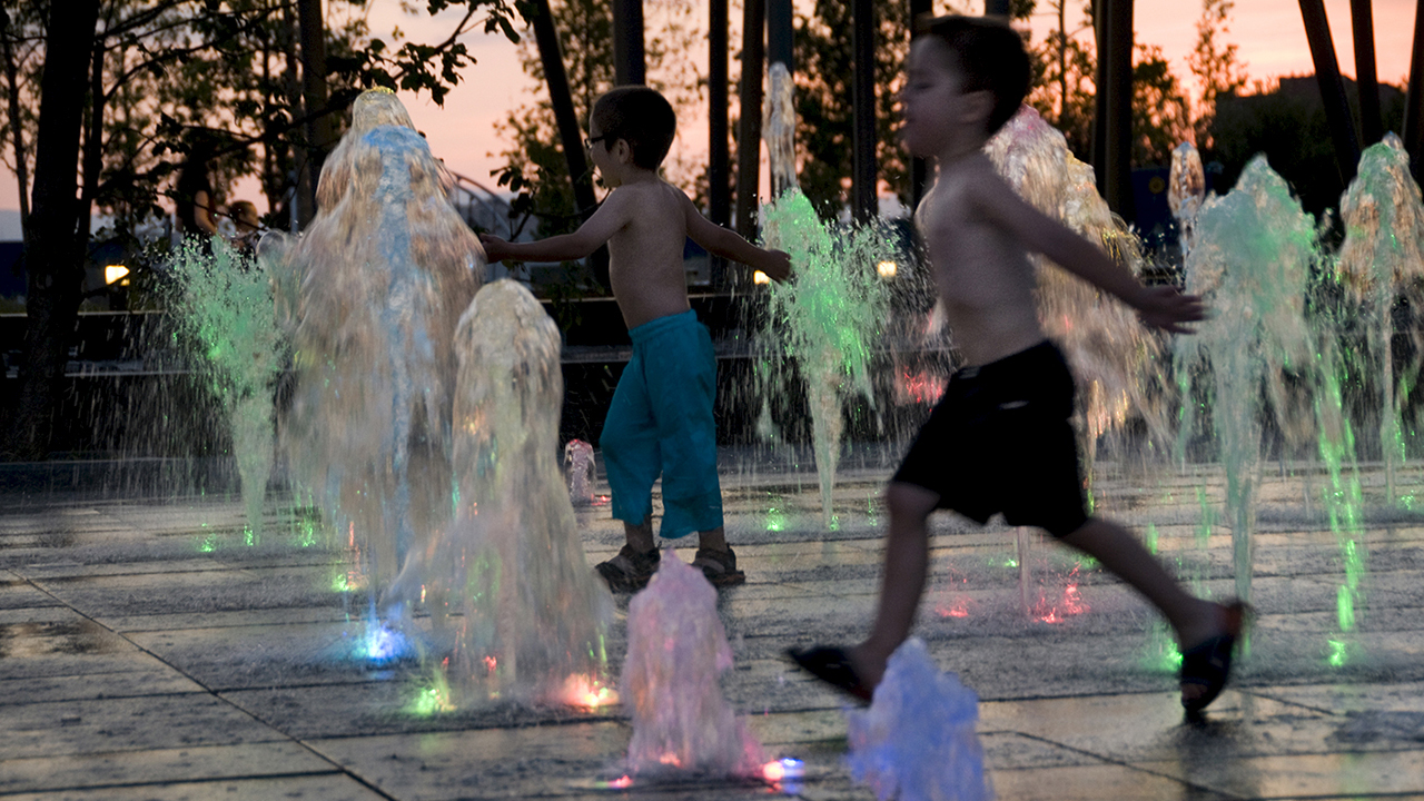 Unos niños se refrescan en unas fuentes a causa del calor