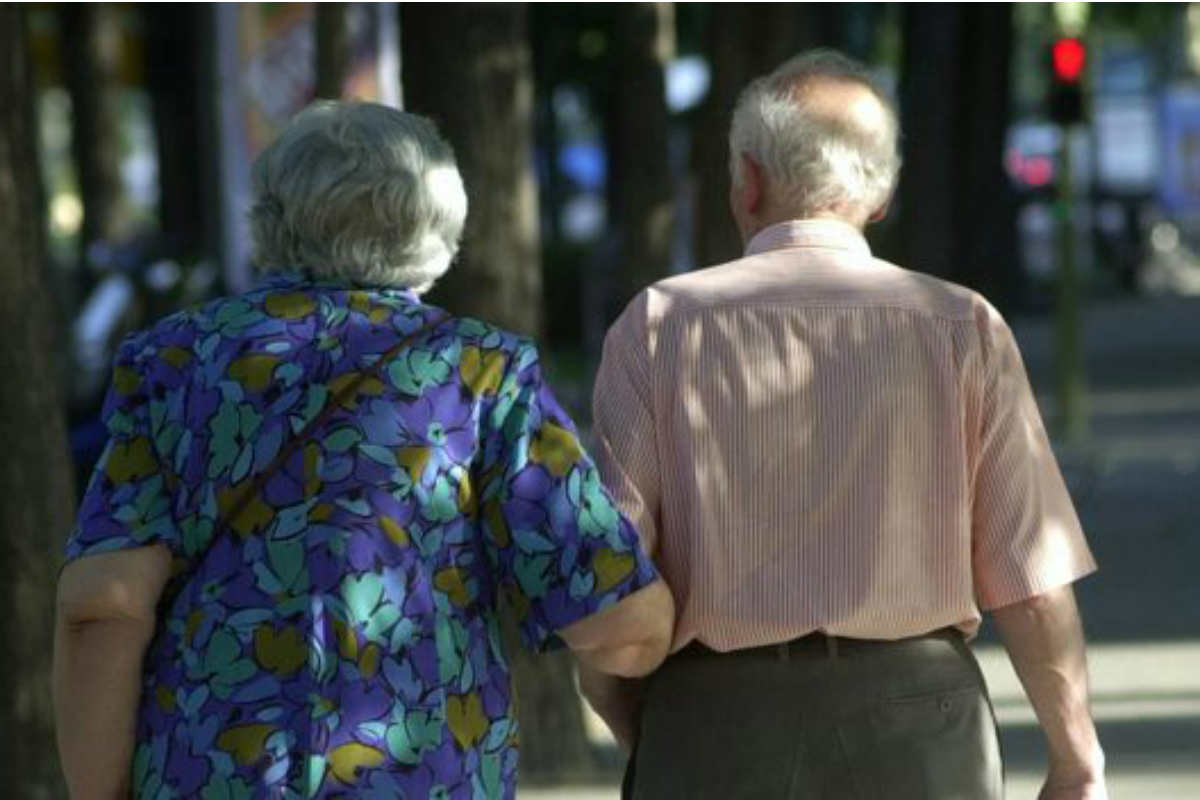 Pareja de mayores paseando de espaldas. 