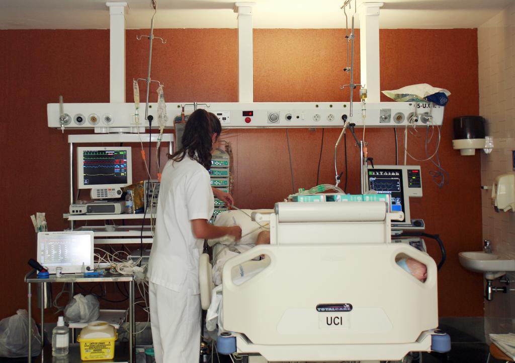 Una enfermera ante la cama de un paciente en la UCI. 