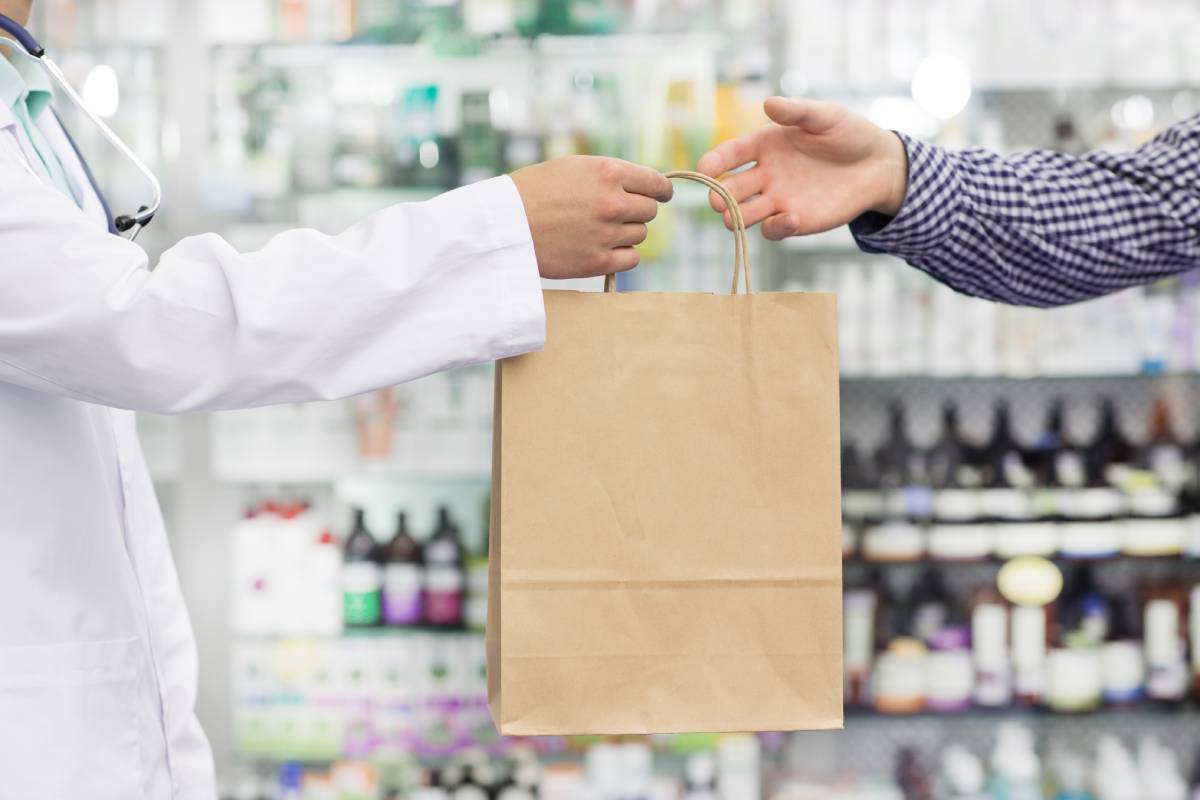 Farmacéutico entrega compra a un cliente 