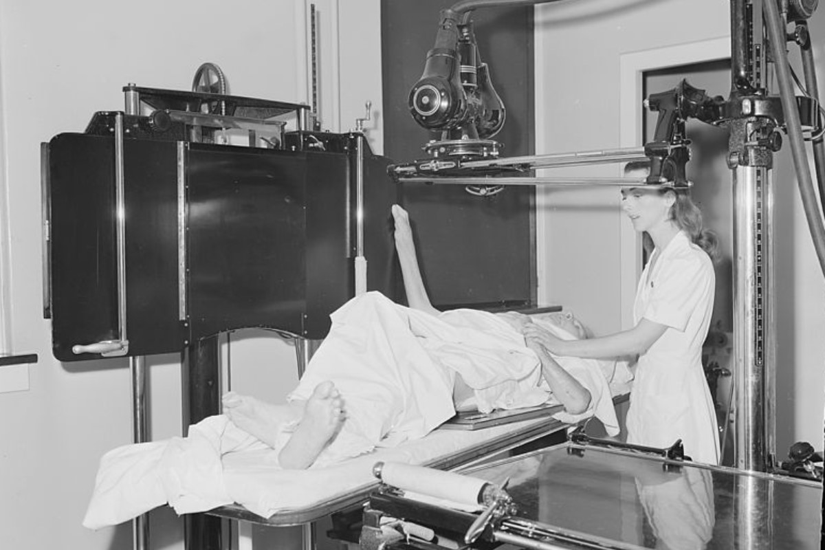 Fotografía antigua de un médico administrando radioterapia a un paciente.