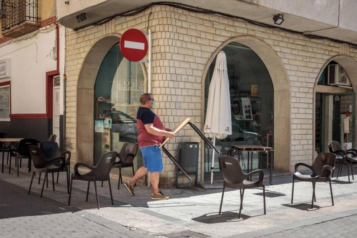 Un hombre recoge las sillas y mesas de la terraza de su negocio en la localidad valenciana de Benigànim (Valencia) , donde Sanidad ha decidido confinar a su población durante 14 días ante el incremento de casos de Covid-19. (EFE/ Biel Aliño) 
