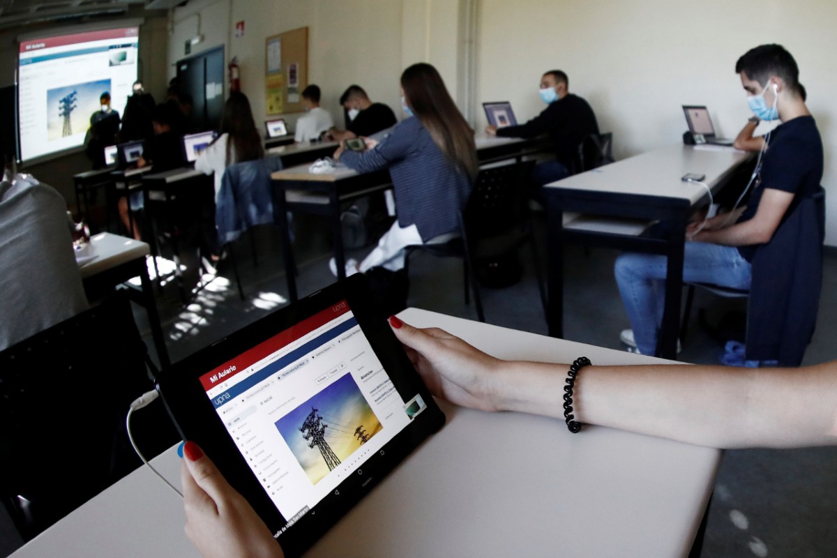 Alumnos de la Universidad Pública de Navarra mirando una clase que se imparte en otra aula distinta desde sus pantallas (EFE/Jesús Diges)