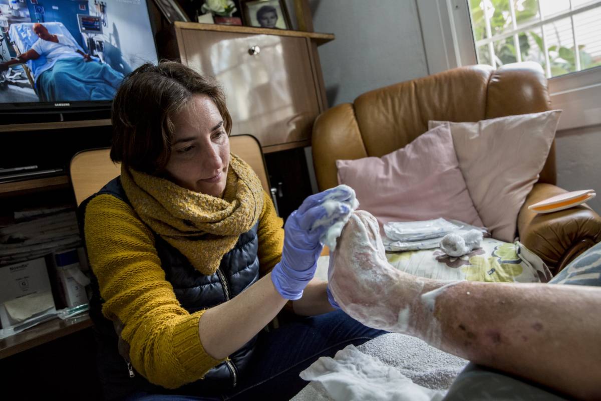 Una enfermera de atención domiciliaria limpia la pierna de la persona atendida en el proceso de curas. (Foto: Ariadna Creus i Àngel García / Banc de imatges infermeres) 