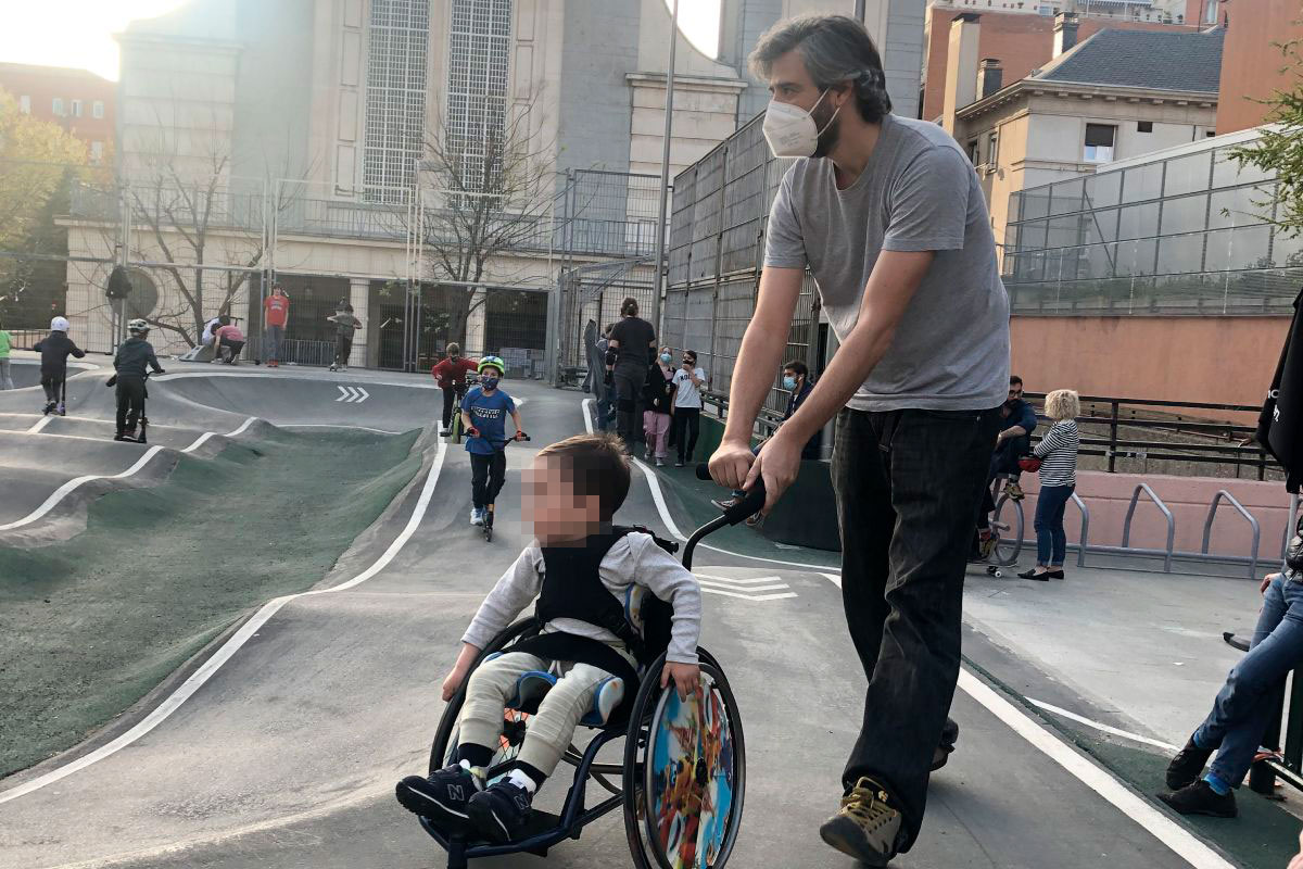 Un niño en silla ruedas paseado por su padre.