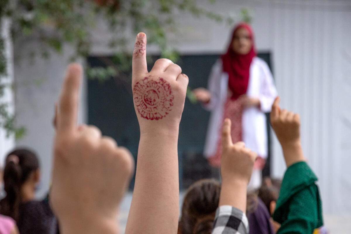 Niñas levantando la mano durante una charla de Rehman en la escuela de educación elemental Barakat, en Attock (Pakistán), donde ella estudió. /Acnur.