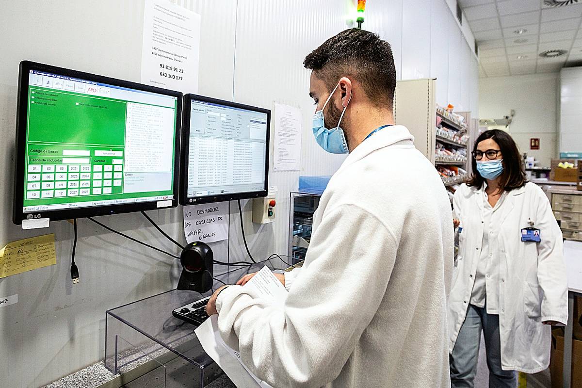 Un farmacéutico del Hospital del Mar (Barcelona), ante la pantalla del ordenador, solicitando la medicación al robot de dispensación. /Jaume Cosialls.