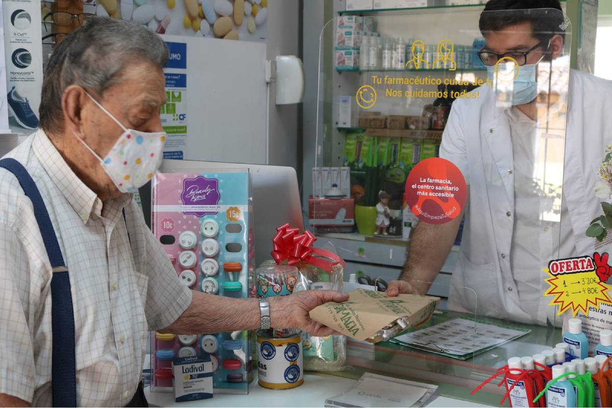 Un farmacéutico atiende a un paciente en una farmacia en Ampudia (Palencia). 