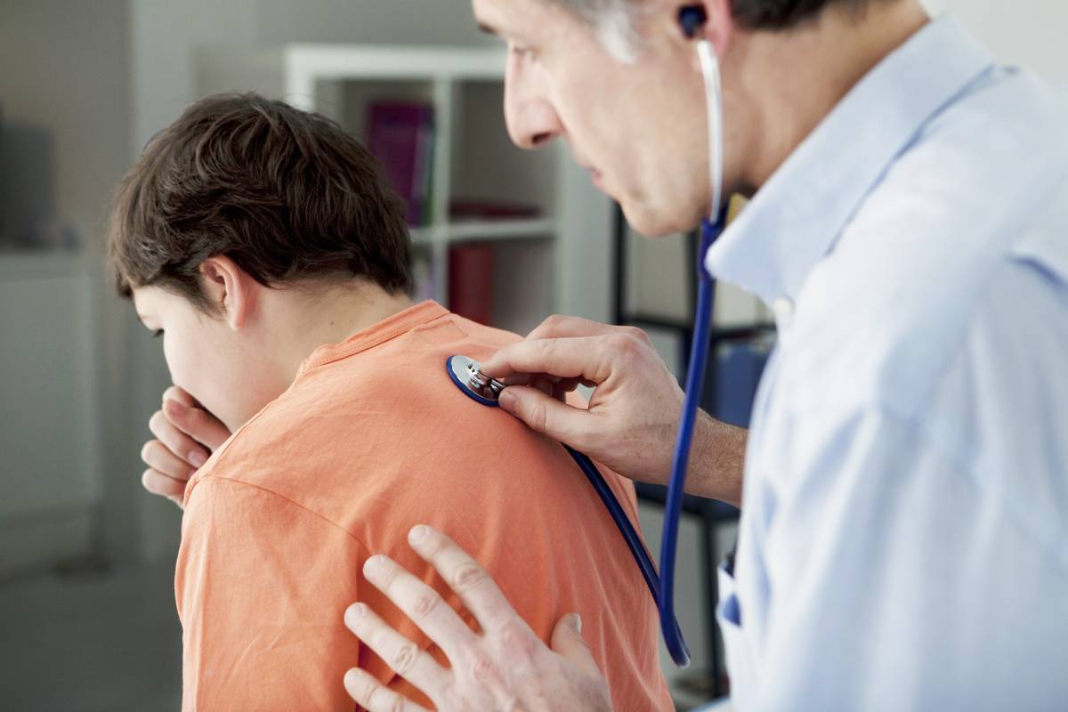 Un médico ausculta los pulmones de un niño.