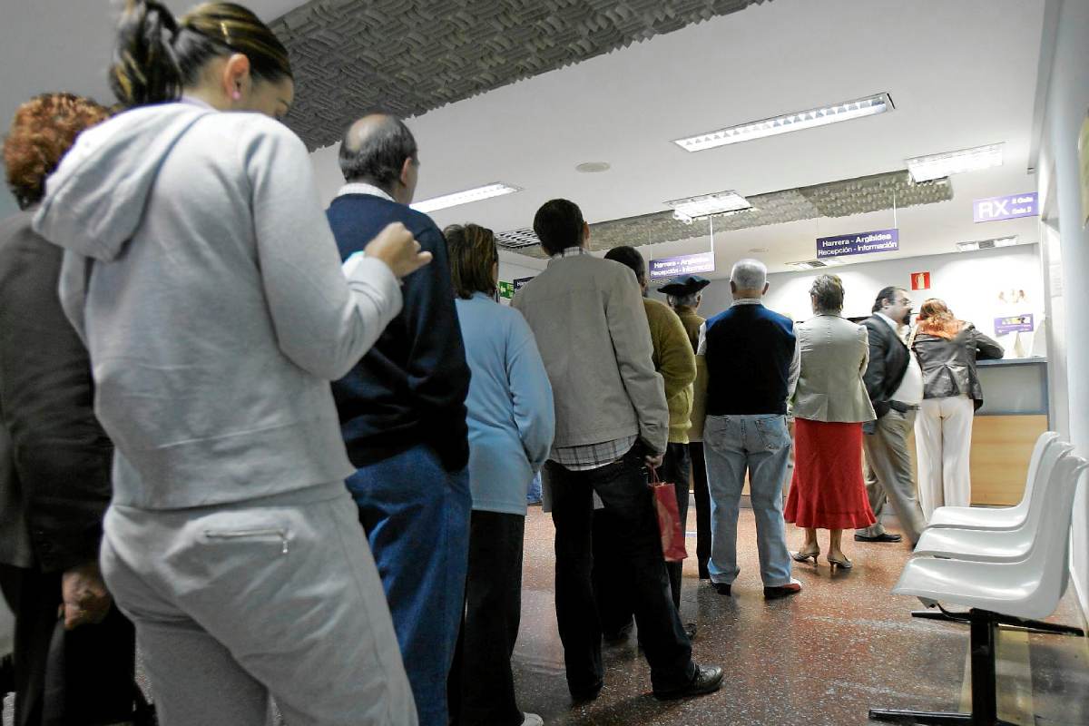 Imagen de archivo de varios pacientes esperando para pedir una cita médica en un ambulatorio. UE 
