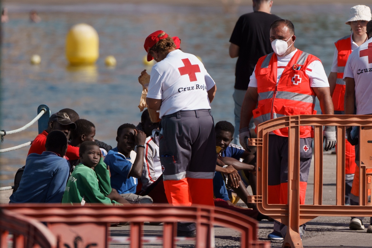 Efectivos de Cruz Roja atienden a niños y adultos llegados en un cayuco al puerto de Los Cristianos, en Tenerife, y remolcado por una embarcación de Salvamar. Foto: EFE/ RAMÓN DE LA ROCHA. 