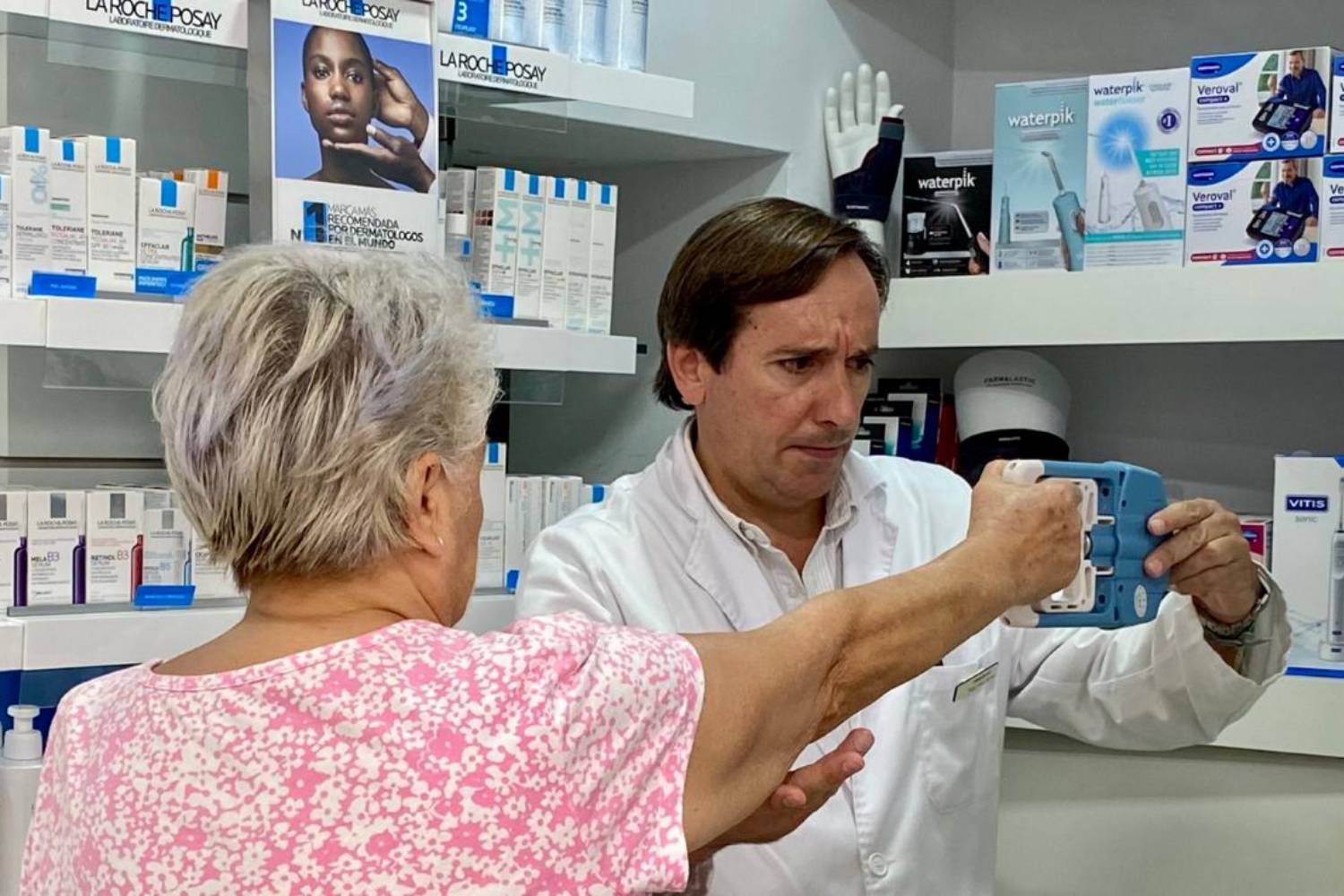 Felipe Mozo, en su farmacia de Cádiz, realizando una prueba de fuera a una paciente. Foto: CF.