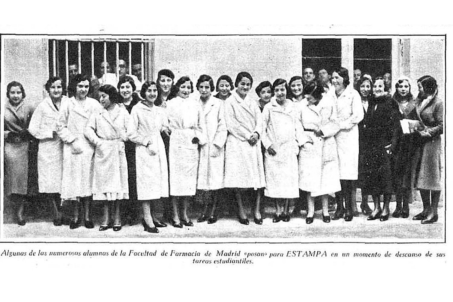 Grupo de mujeres vestidas con batas blancas posan juntas frente a un edificio.