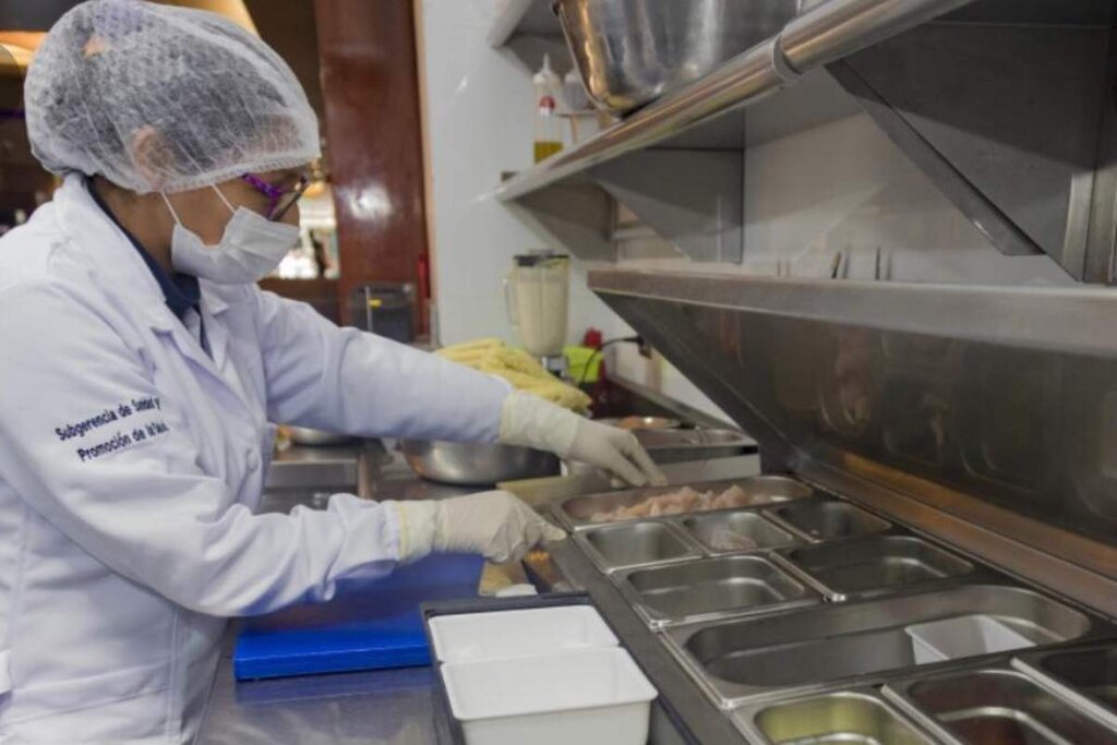 Farmacéutica verificando la temperatura de los alimentos (algunos al 'baño María') en un restaurante.