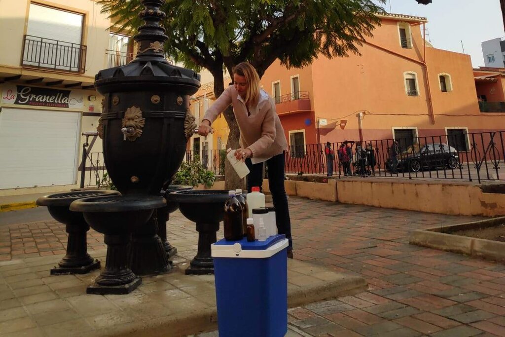 Una farmacéutica de Salud Pública tomando muestras de agua de la fuente de un pueblo para realizar su posterior analítica.