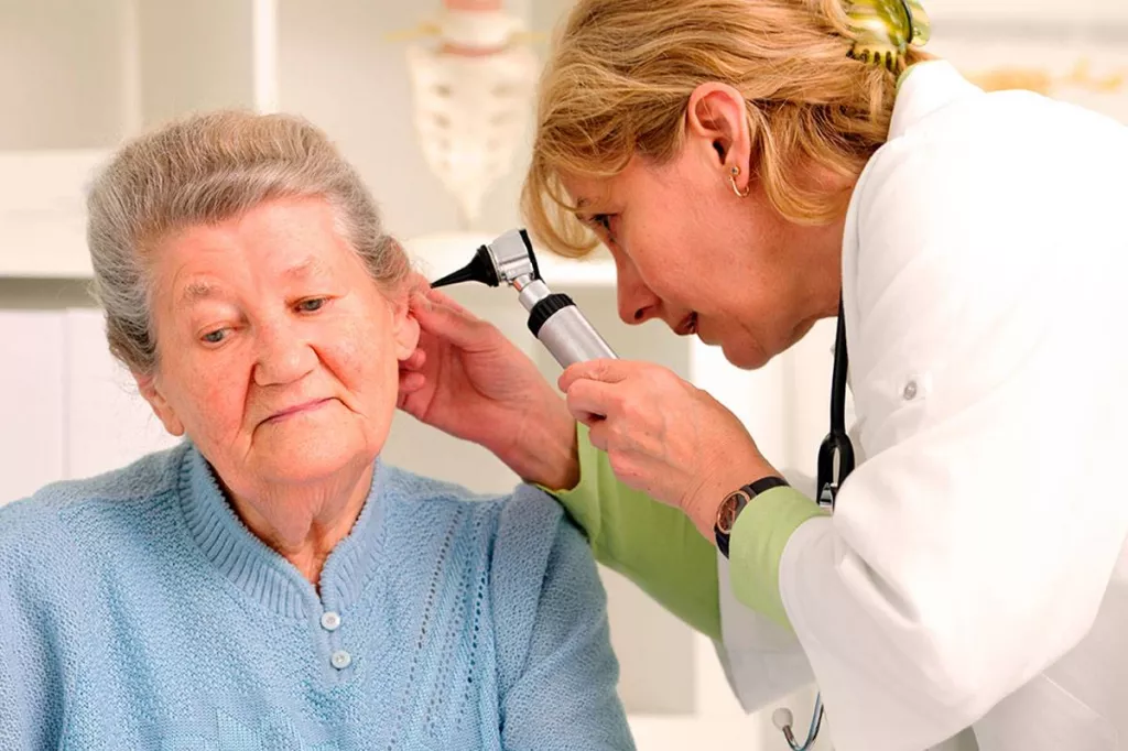 Una médico examina el oído de una paciente.