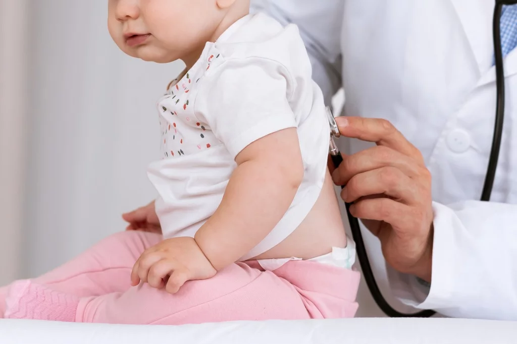 Médico auscultando a un paciente lactante.
