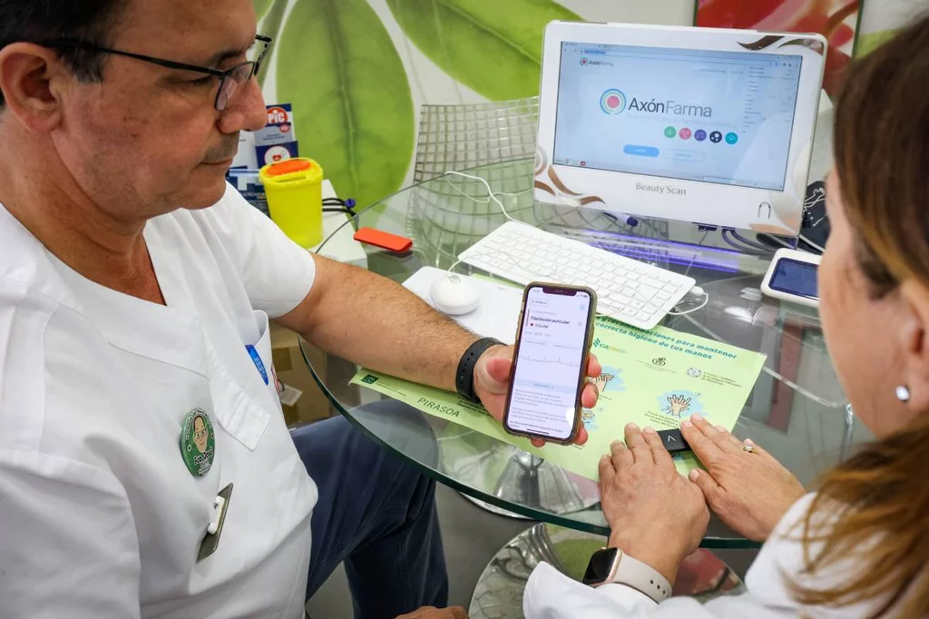 Francisco MarÃn, impulsor de 'AxÃ³nIctus', en su farmacia, muestra cÃ³mo hace un 'electro' con el dispositivo 'Kardia'. Foto: ÃRABA PRESS/CÃDIZ.