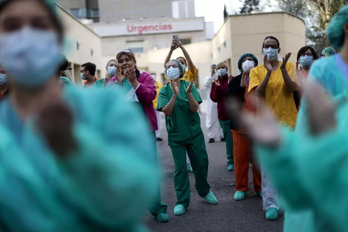 Varios profesionales sanitarios aplauden a las puertas de un hospital madrileño (Fotografía: Alberto Di Lolli).