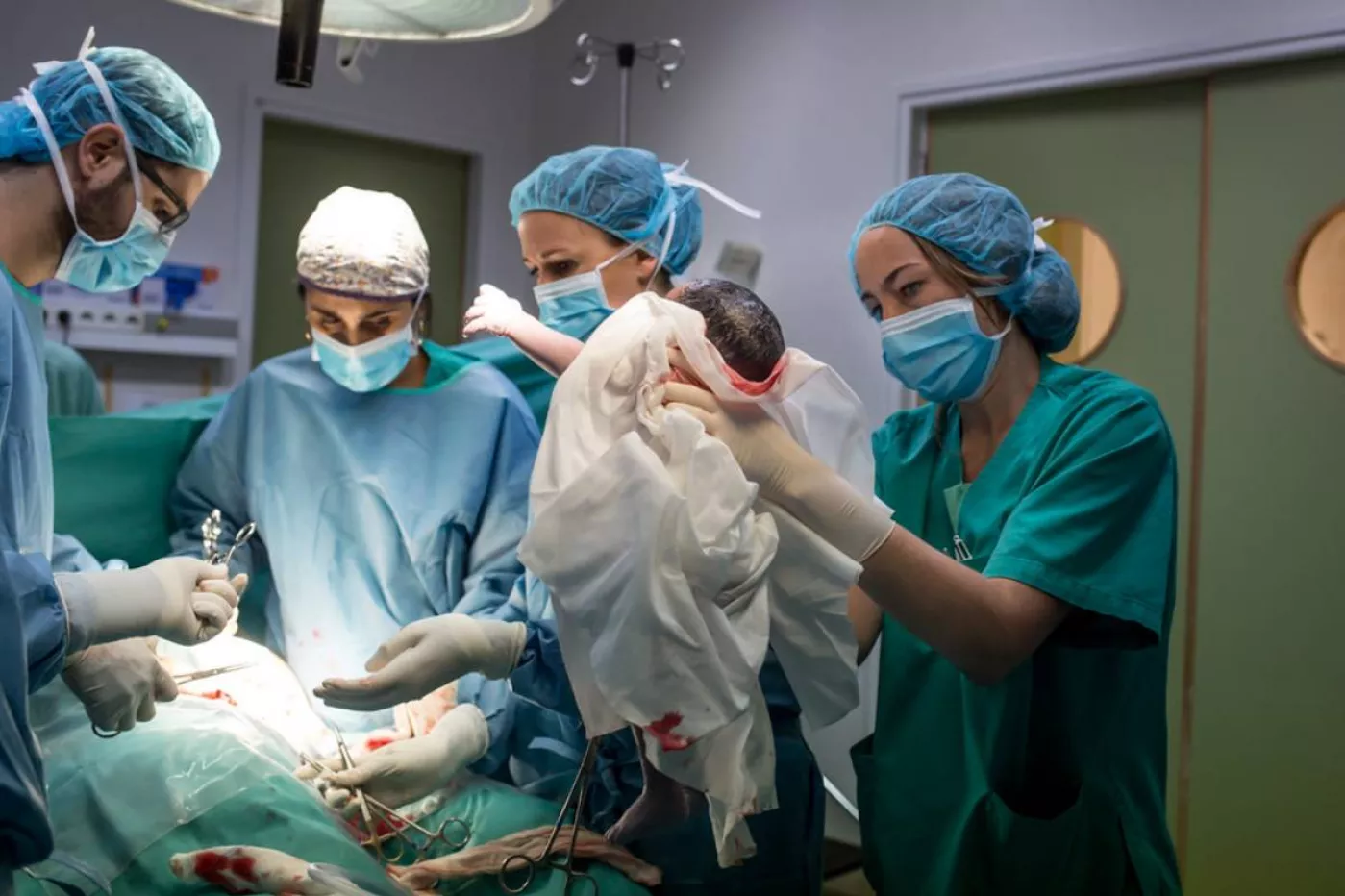 Matronas y otros profesionales sanitarios, atendiendo un parto por cesárea. FOTO: Ariadna Creus y  Ángel García (Banc Imatges Infermeres).