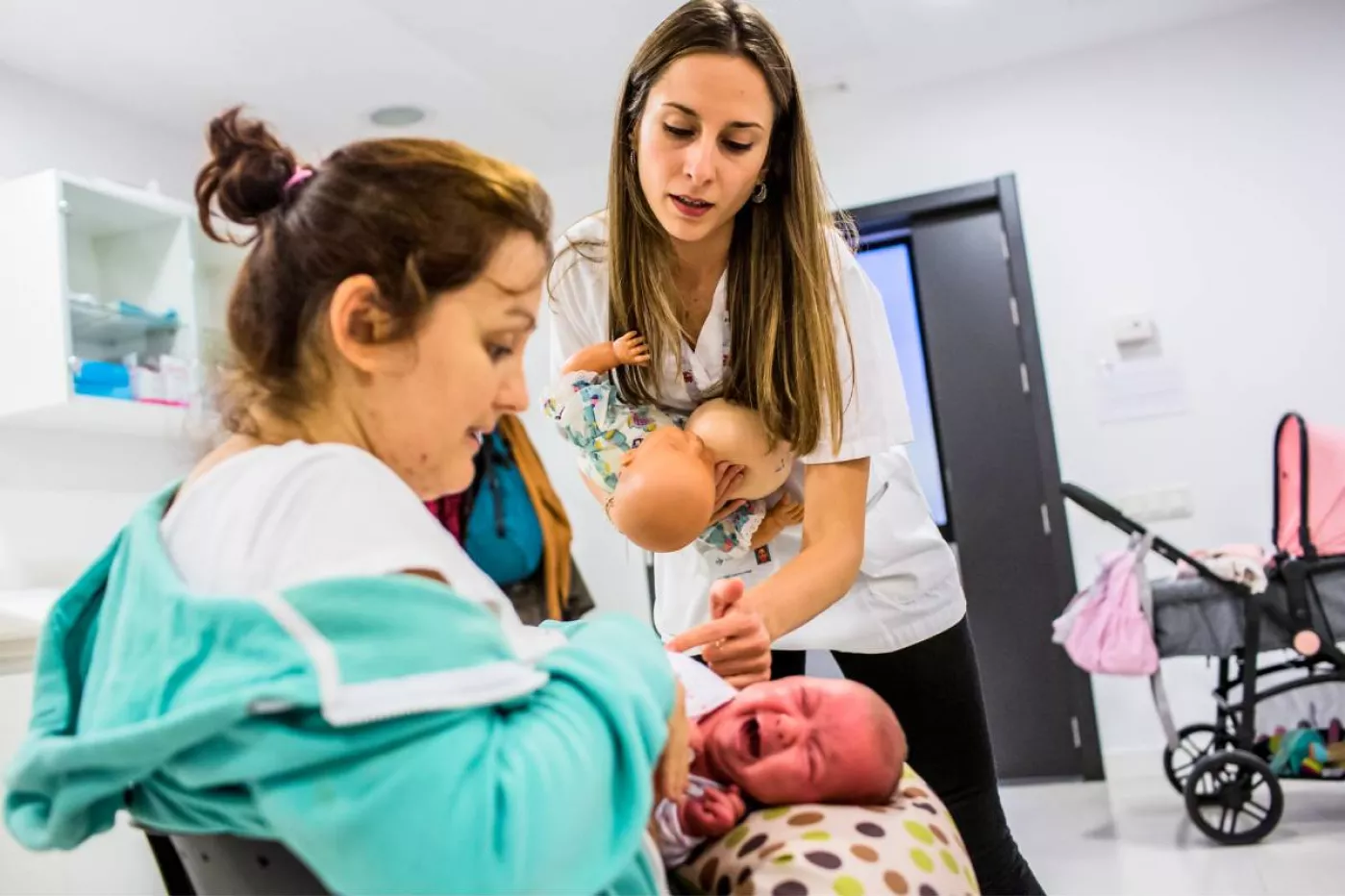 Una matrona ayuda a una madre a coger la posición adecuada para dar el pecho a su hijo recién nacido. Fotografía: Ariadna Creus y Ángel Gracía (Banc Imatges Infermeres).
