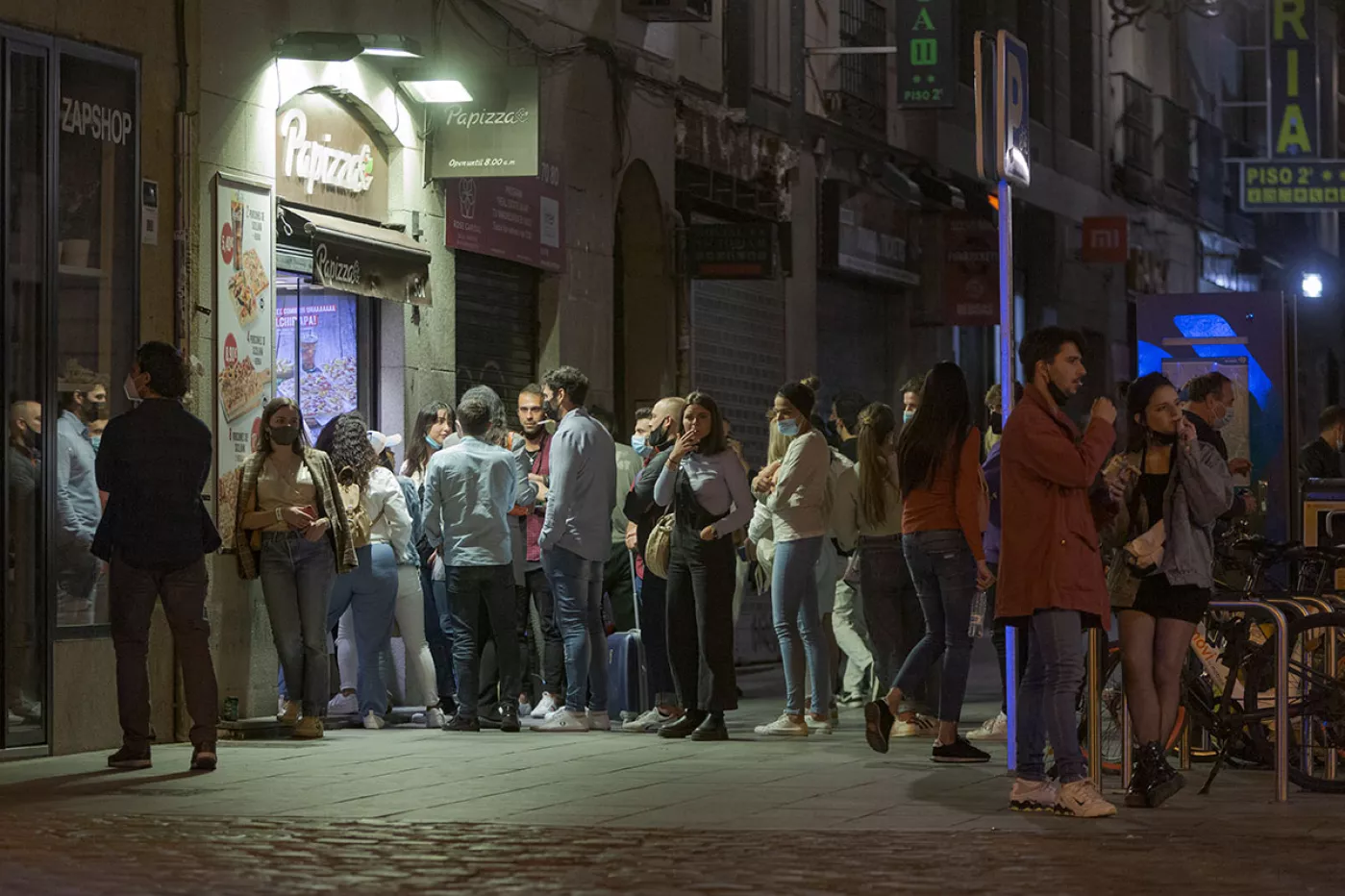 Un grupo de jóvenes hacen cola frente a un establecimiento de madruga en una calle de Madrid. 