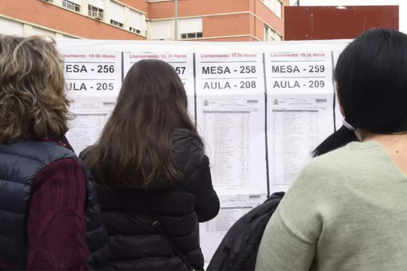 Varias aspirantes consultan el listado de mesas para el examen MIR de 2022, a la puertas de una de las sedes del examen, en Madrid. Foto: JOSÉ LUIS PINDADO.