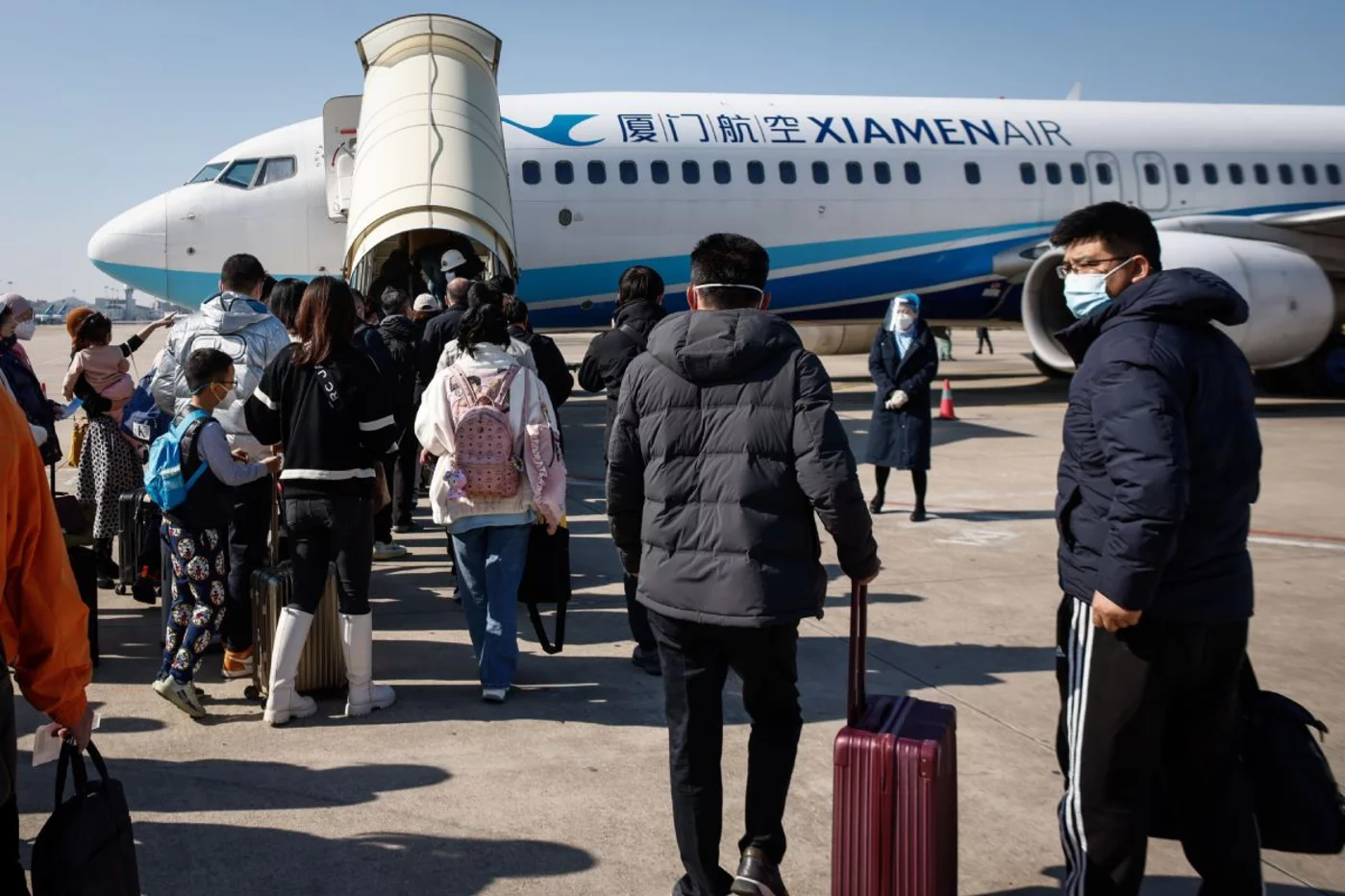 Los pasajeros con destino a Beijing abordan un avión en el aeropuerto internacional Xiamen. Foto: EFE.