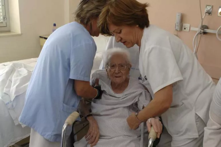 Enfermeras atendiendo a una anciana.