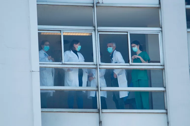 Profesionales sanitarios al lado de la ventana de un hospital.