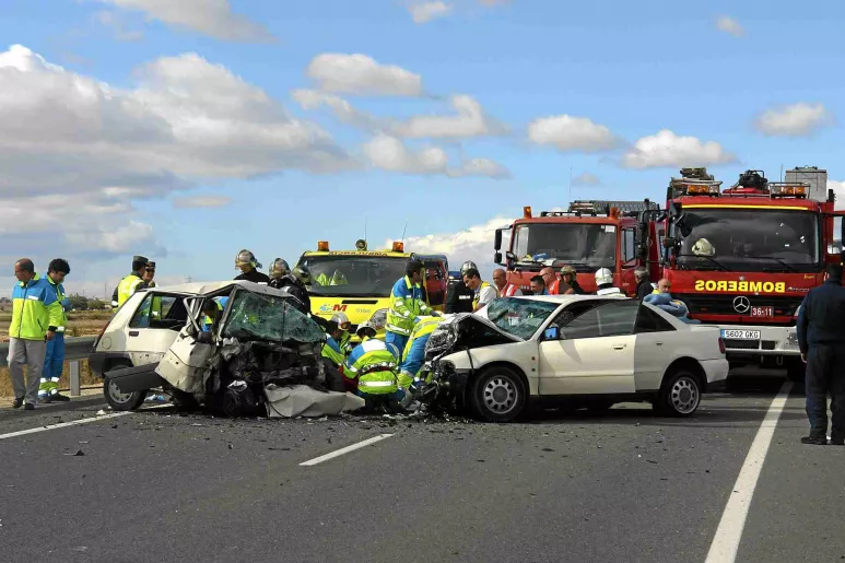 Dos coches en un accidente de tráfico, con ambulancias, personal médico y bomberos.