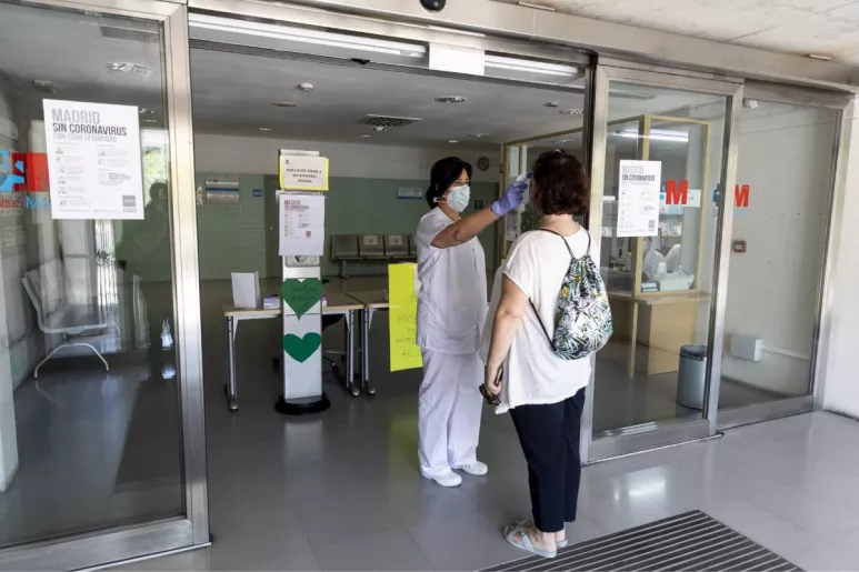 Una enfermera toma la temperatura a una paciente a la puerta de un centro de salud de la Comunidad de Madrid (Foto: Alberto Di Lolli).