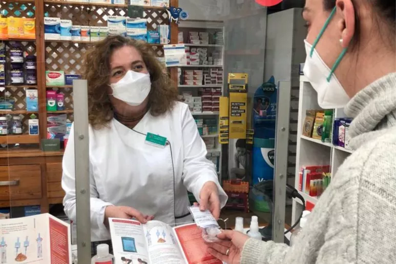 Una farmacéutica de Murcia entregando un test de cribado de cáncer de colon. 