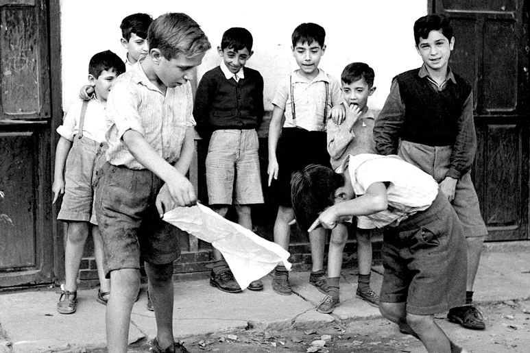 Un grupo de niños juega a torear novillos en la calle.
