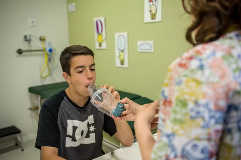 Una enfermera ayuda a un adolescente a usar un inhalador. Foto: BANC IMATGES INFERMERES (ARIADNA CREUS Y ÀNGEL GARCÍA)