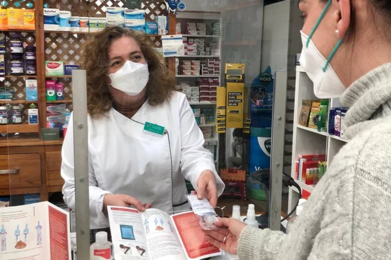 Una farmacéutica de Murcia entregando un test de cribado de cáncer de colon.
