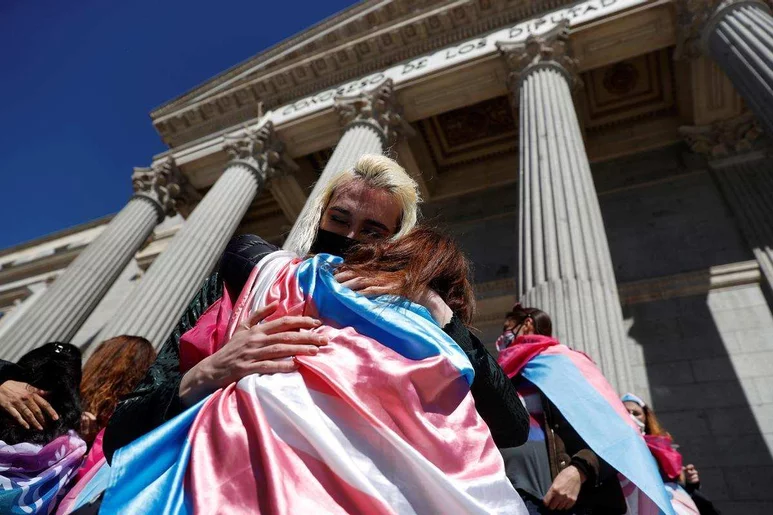 Dos representantes del colectivo LGTBI se abrazan ante las puertas del Congreso de los Diputados tras la definitiva aprobación de la 'ley trans' el pasado mes de febrero. Foto: EFE/MARISCAL.
