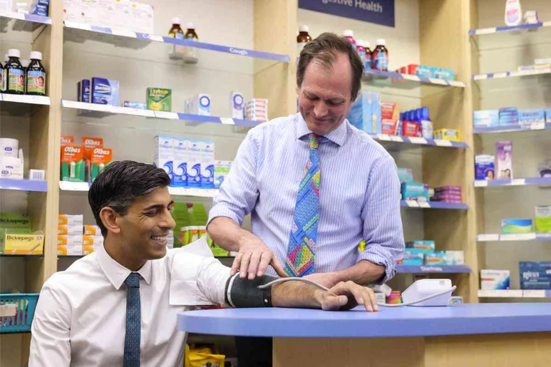El primer ministro del Reino Unido, Rishi Sunak, tomándose la presión arterial en una farmacia británica. Foto: GOBIERNO DE REINO UNIDO.