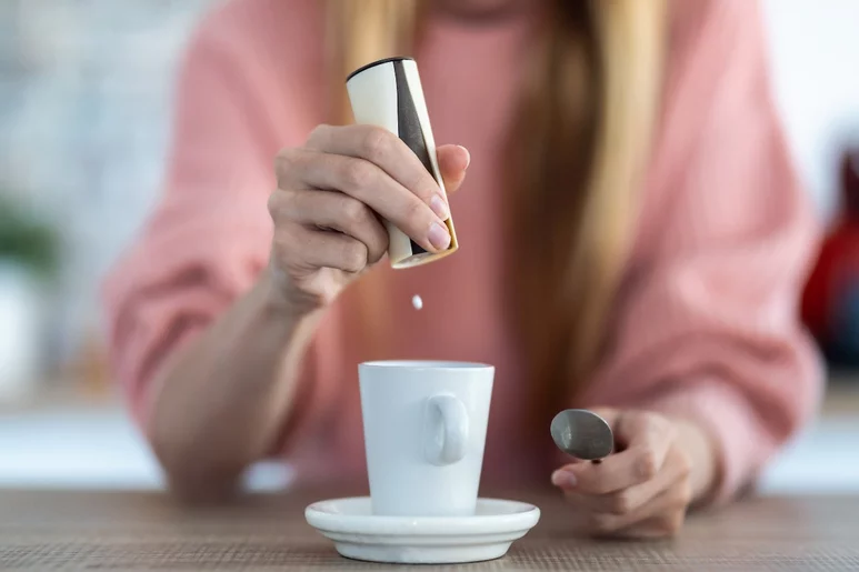 Una mujer utiliza un edulcorante con aspartamo para endulzar el café. Foto: SHUTTERSTOCK.
