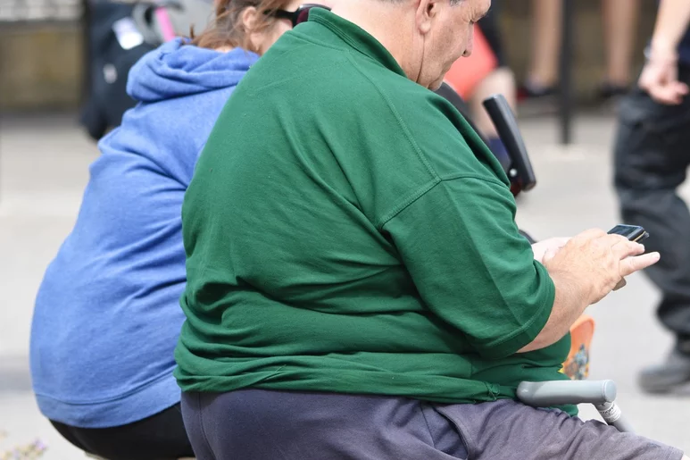 Una pareja de personas con obesidad sentados en un banco. Foto: SHUTTERSTOCK.